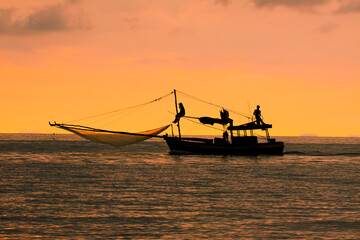 silhouette of domestic fishery boat in thailand against beautiful sunset sky