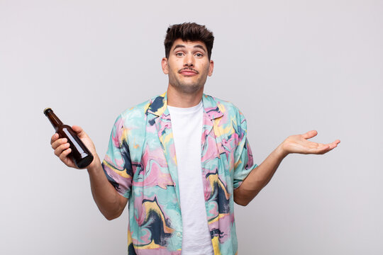 young man with a beer feeling puzzled and confused, doubting, weighting or choosing different options with funny expression