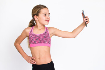 Beautiful young sport and healthy girl in sportswear taking selfie with smartphone. Isolated photo on white background with copy space.