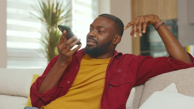 At sunlight african american young man recording voice message use phone in social network. Talking smiling using wifi indoors communicate technology microphone speaker. Slow motion