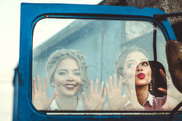 Portrait of two young girls dressed in retro clothes at the door of a large old country car.