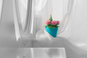 Cute felt  roses in a blue pot against a background of flying white curtains, a mirror.  Dressing table concept.