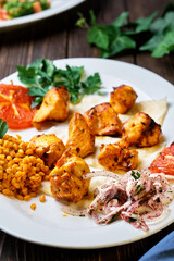 Light and delicious grilled chicken kebab, located on a platter with tomato and bulgur, decorated with cilantro sprigs. Healthy and tasty oriental cuisine. Close-up, shallow depth of field