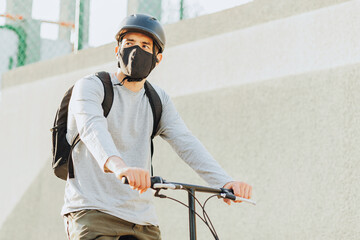 Cyclist man wearing face mask in the city. Concept of bicycles as a safer form of transportation during the New Normal