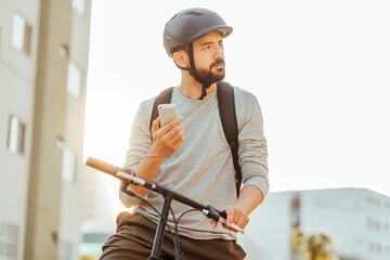 Cyclist standing looking at his smartphone in the city. Concept of using gps map or delivery apps
