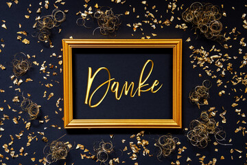 Frame With German Text Danke Means Thank You. Golden Christmas Decoration And Ornament. Black Background With Glitter And Sparkle