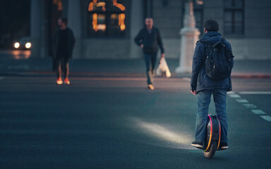 Man riding fast on electric unicycle through crosswalk at night with diode lights. Mobile portable individual transportation vehicle. Night riding, man on electric mono-wheel riding fast (EUC) © Tricky Shark
