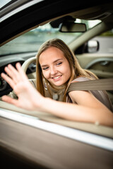 Fototapeta na wymiar Cute female teen driver enjoying her freshly acquired driving license at the wheel of her first car