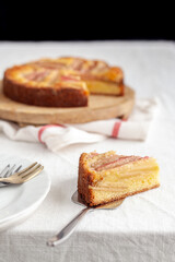 A slice of a rhubarb and custard pie on white table cloth