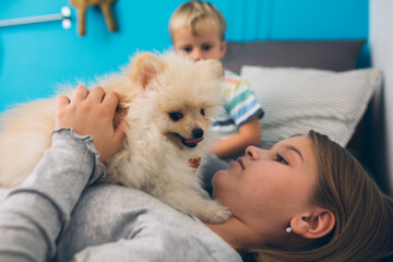 brother and sister playing with cute little puppy at home