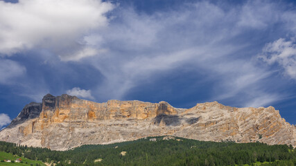 Fototapeta premium Full view of Sasso di Santa Croce mountain range, its west 900 m vertical wall and Mount Cavallo, overlooking Badia valley, from La Villa village, Alta Badia, Eastern Dolomites, South Tirol, Italy.