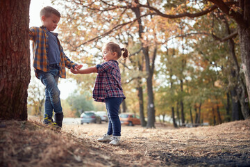 Little brother and sister playing in the woods