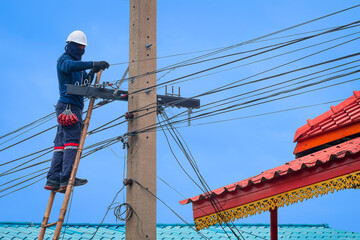 Asian technician on wooden ladder is installing cable lines to connect telephone and internet...