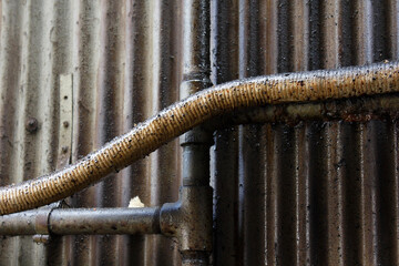油汚れのトタン壁と配水管