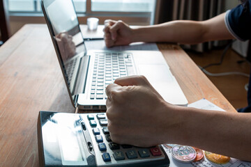 Close up of businessman or accountant hand on calculator to calculate and laptop, working on financial data report. Businessman working with calculator, business document and laptop computer notebook.