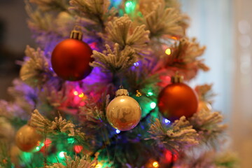 Obraz na płótnie Canvas Die bunten und verschwommenen Lichter eines kleinen und weißen Weihnachtsbaumes stehend auf einem roten Tuch.
