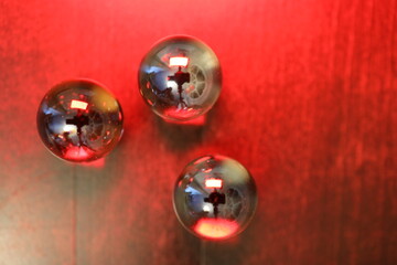 Große und glänzende Glaskugeln in verschiedener Anzahl auf einem braunen Holztisch. Sie repräsentieren die vier oder fünf Elemente.
