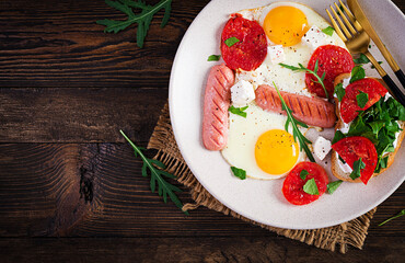 English breakfast - fried eggs, sausages, tomatoes and feta cheese. American food. Top view, overhead, copy space