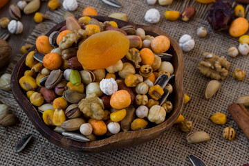 Mixed,crispy, dry nuts in a wooden plate on wooden table,with dried fruits,rustic design