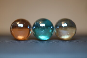 Große und glänzende Glaskugeln in verschiedener Anzahl auf einem braunen Holztisch. Sie...
