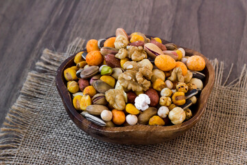 Mixed,crispy, dry nuts in a wooden plate on wooden table,with jute napkin