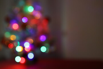 Die bunten und verschwommenen Lichter eines kleinen und wei&szlig;en Weihnachtsbaumes stehend auf einem roten Tuch.