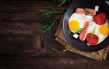 English breakfast - fried eggs, sausages, tomatoes and feta cheese. American food. Top view, overhead, copy space