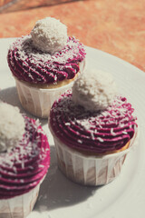 Delicious cupcake with violet cream decorated with balls topped with coconut crumbs