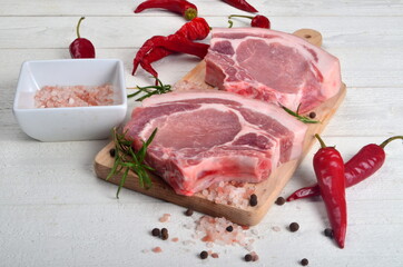 Sliced raw pork steak with spices an red pepper on white wooden background. Top view
