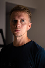 Obraz premium Portrait of a young blond man in a dark room with shadows