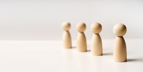 Abstract wooden toy figures stand in a row on a white background. Concept of employees in a team