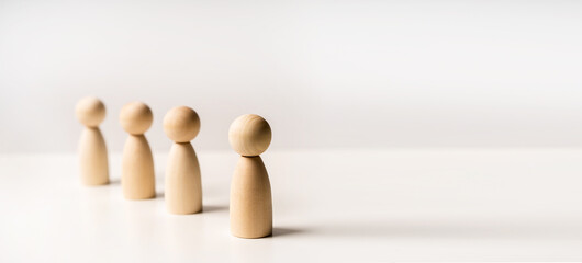 Abstract wooden toy figures stand in a row on a white background. Concept of employees in a team