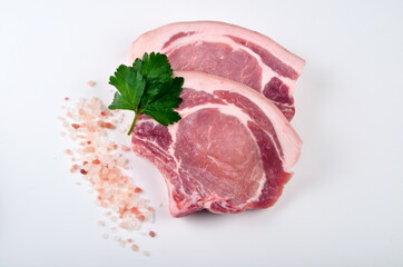 Sliced raw pork steak isolated on white background. Top view. Sliced raw pork steak with green perslay and pink salt