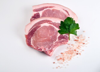 Sliced raw pork steak isolated on white background. Top view. Sliced raw pork steak with green perslay and pink salt