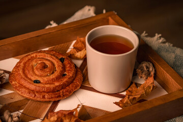 Cozy autumn in the house, tea party with a cinnamon bun and tea on a tray