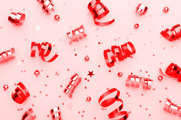 Red festive background with shining confetti, baubles and ribbons.