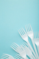 Many plastic forks on a blue background. Vertical foto.