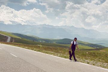 guy in black jeans and a cap carries a skate