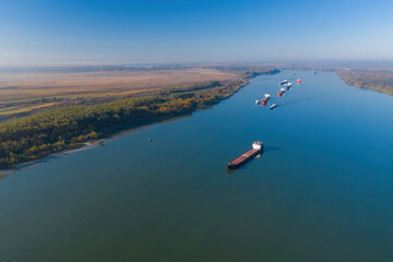 Aerial shot of the autumn forest and river with ships. Dramatic unusual scene. Autumn landscape....