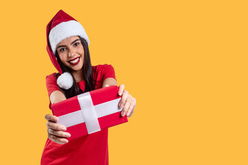 Woman with Christmas hat holding a gift, isolated on yellow background