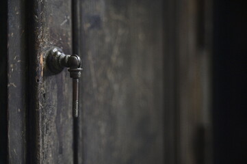 Close-up of the black iron door handle on the wooden cabinet door against a blurred background.