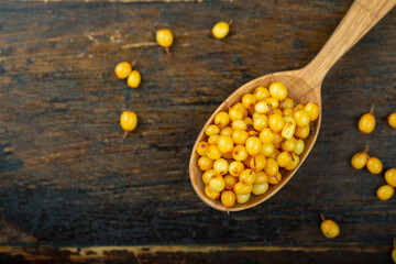 Sea buckthorn in a wooden spoon on a wooden table.
