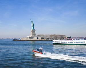 Statue of Liberty with racing US Coast Guard Patrol boat,  tourist boat, and bright blue sky