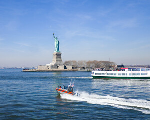 Statue of Liberty with racing US Coast Guard Patrol boat,  tourist boat, and bright blue sky © Gerald Zaffuts