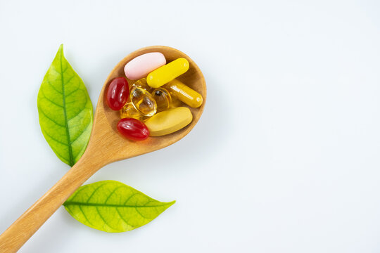 capsule and vitamin organic supplements good for health in wood spoon on white background with copy space, medicine and drug concept