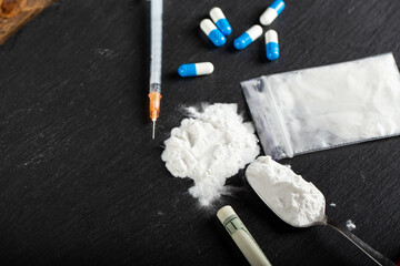 white powder and drugs in pills dope and syringe on the table.
