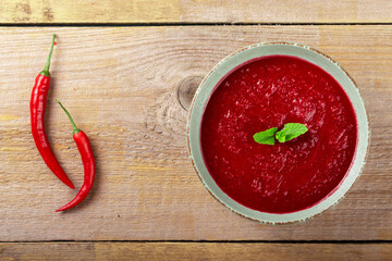 Tasty appetizing summer tomato soup puree gazpacho with tomatoes and cucumbers served in bowl on wooden background.