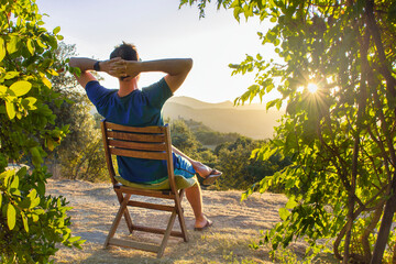 idyllic and rural scene. A man chilling and resting after hiking sitting on a wooden chair and...