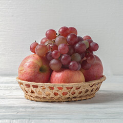 Fresh fruits grapes and apples in a basket on the table.