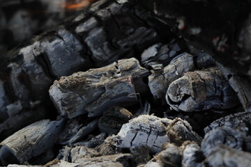 Smoldered logs burned in vivid fire close up. Atmospheric background with flame of campfire. Unimaginable detailed image of bonfire from inside with copy space. Whirlwind of smoke and glowing embers.
